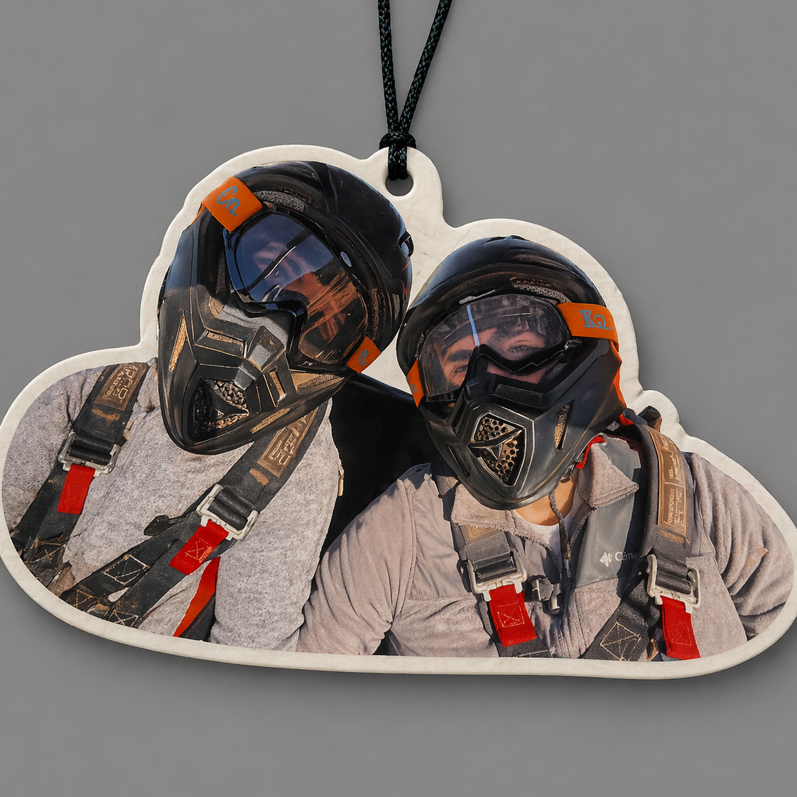 Heart-shaped keychain with two people wearing helmets and gear on a gray background